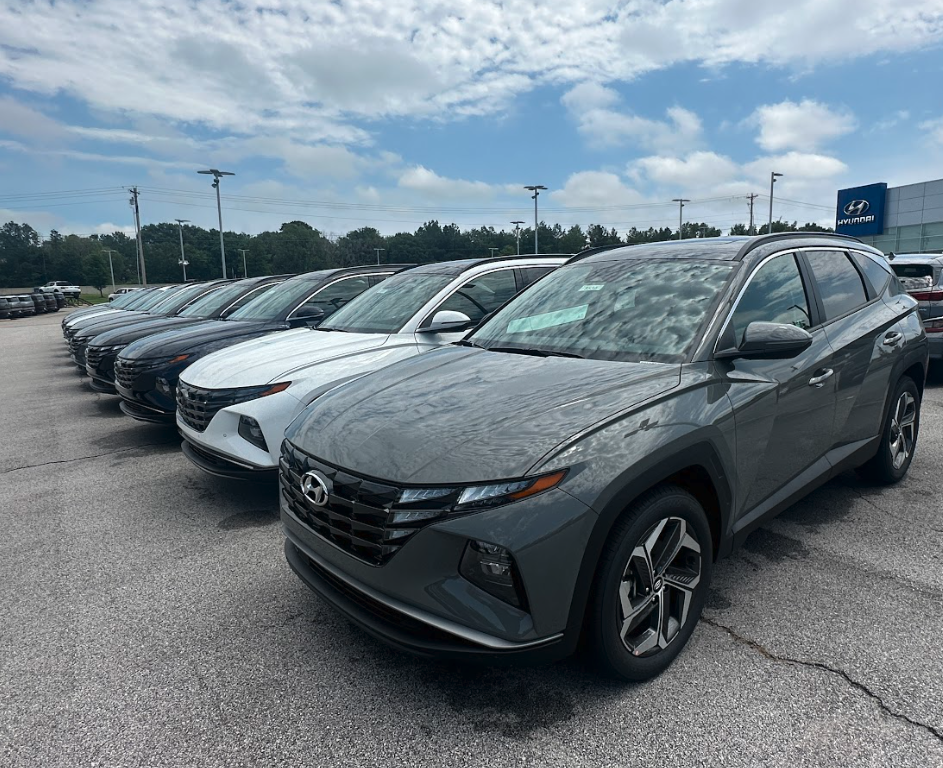 Lineup of Hyundai SUVs parked outside Crain Hyundai of Fayetteville under a partly cloudy sky